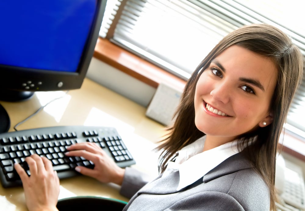 Business woman portrait smiling in an office in front of her desktop computer