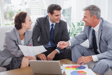 Cheerful business people analyzing financial graphs of their company in cosy meeting room