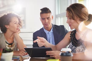 Image of three succesful business people using a tablet during at meeting